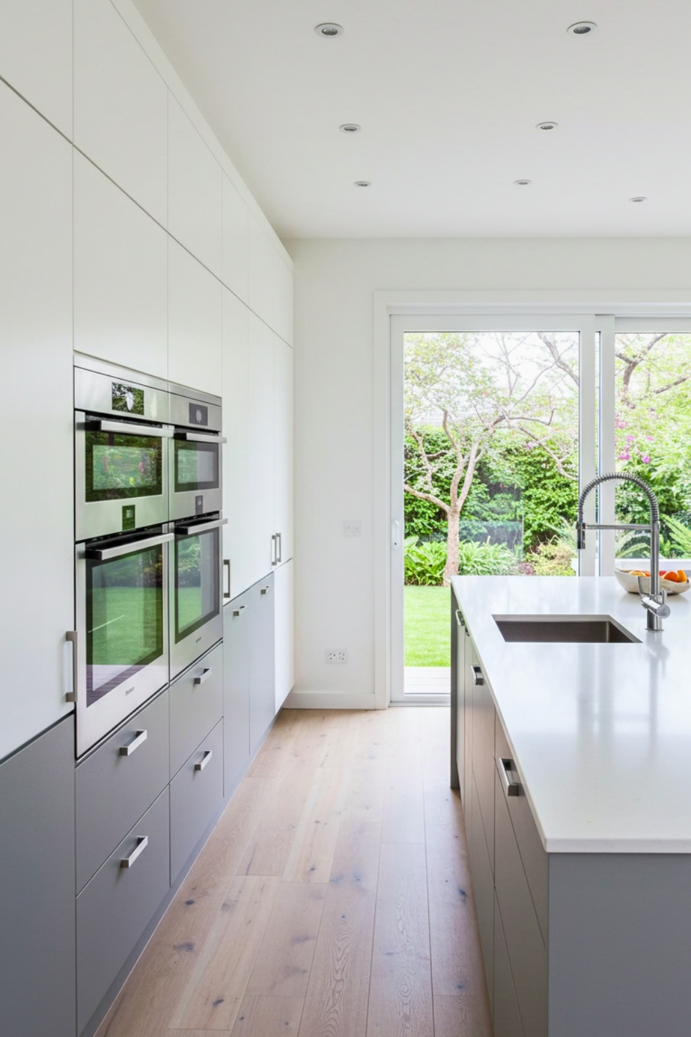 A Sleek Minimalist U Shaped Galley Kitchen White Flat Panel Upper Cabinets