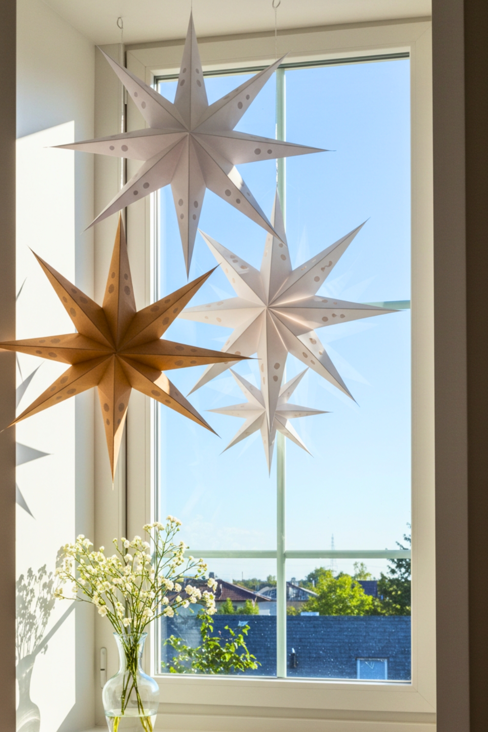 A Sunlit Windowsill With Large Multi Point Paper Stars Hanging From The Ceiling